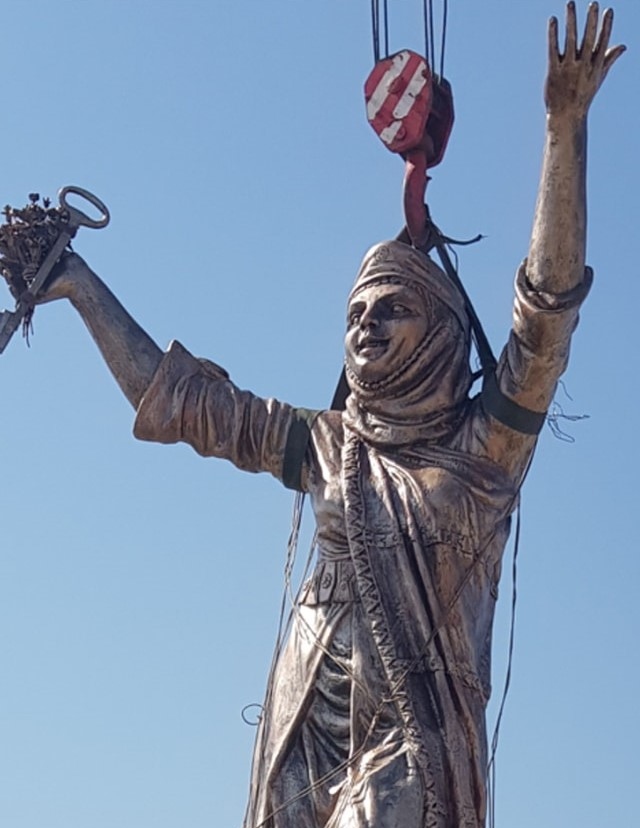 The statue of the folkloric woman being airlifted into place