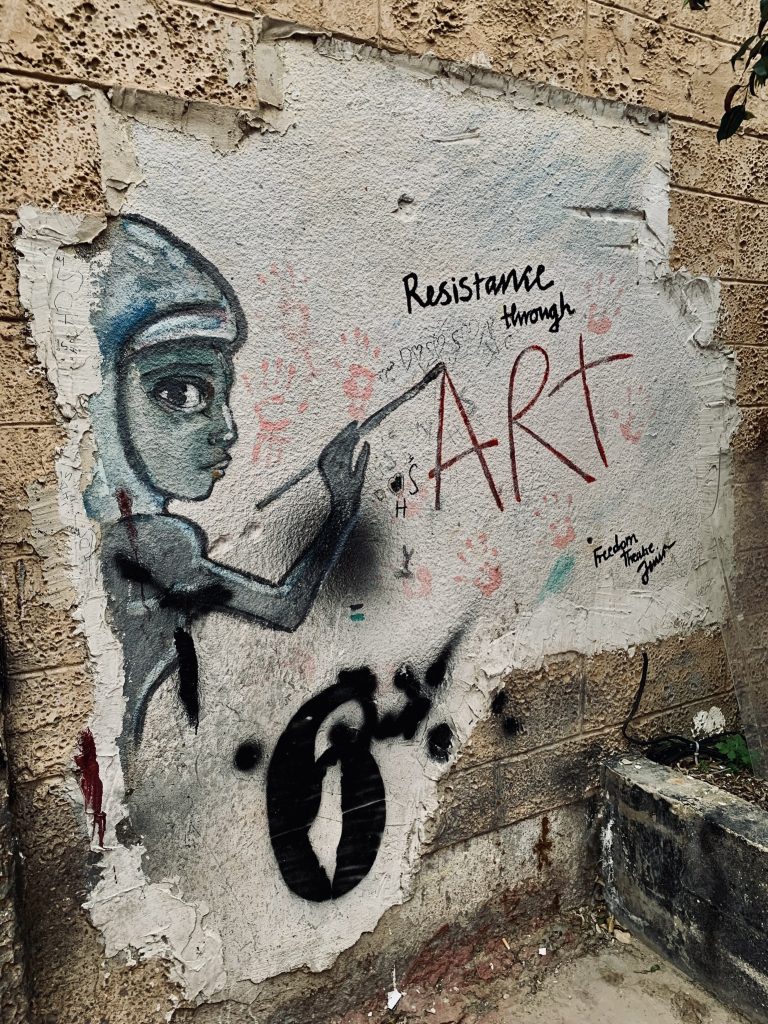 A painting on the wall of a person painting the words 'Resistance through art'