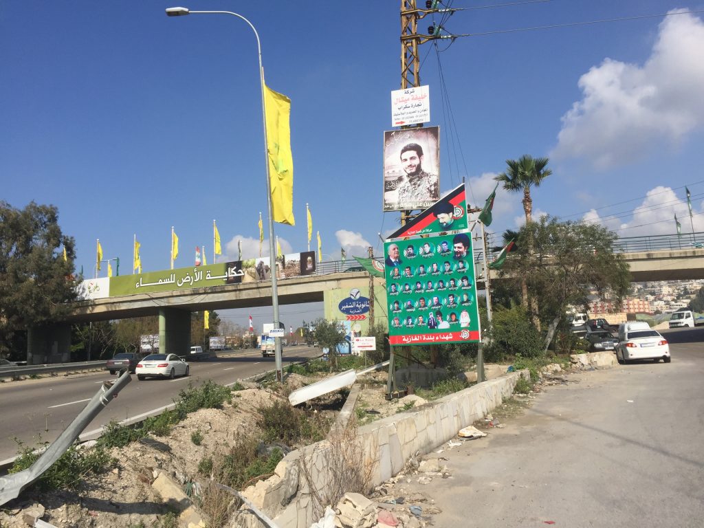 A roadside banner with men's faces on it